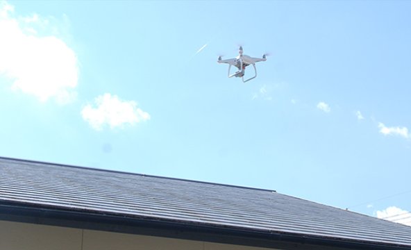 屋根の上空を飛行するドローン