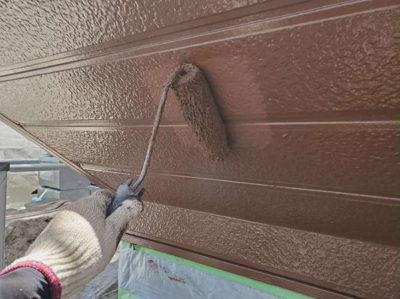 【鉄板サイディング】上塗り塗装<br />
<br />
より強靭な塗膜を形成して、耐候性や仕上がりを良くするため、もう一度塗装を施します。