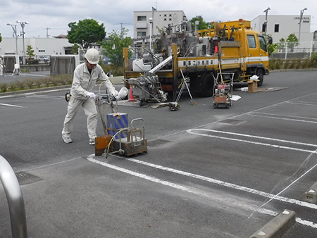 【施工中】<br />
奥に見えるトラックにある溶融釜で、粉体樹脂塗料を高温で溶かし、液体化させたものを機械で塗布してラインや文字を書いています。ラインや文字は、冷めると固体化する物で、タイヤによる摩耗や衝撃に強く、耐久性に優れています。