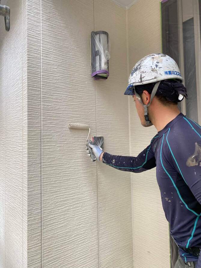 <strong>中塗り塗装</strong><br>ラジカル制御形シリコン樹脂塗料で着色を行います。チョーキング現象抑制効果により、長期に渡って美観を保ちます。なお、水性タイプの為、作業性が良く、環境にも優しい塗料です。 表面に水がなじみ、水滴にならずに水膜ができる現象を起こします。汚れを浮かせて洗い流すセルフクリーニング効果もあります。