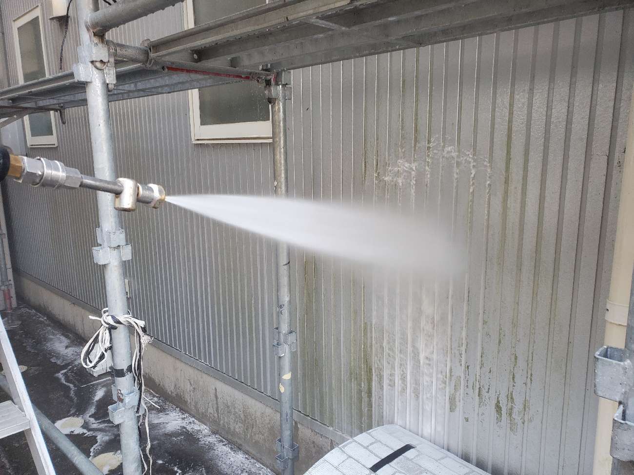 <strong>バイオ洗浄中</strong><br>通常洗浄では取り切れない根っ子の部分まで働きかけます。洗浄不十分の下地は、塗装した塗料を栄養にしてカビやコケが塗装前の数倍の量に繁殖する場合があります。バイオ洗浄は細かい部分に潜んでいるカビやコケ、藻や汚れを徹底的に洗い流します。